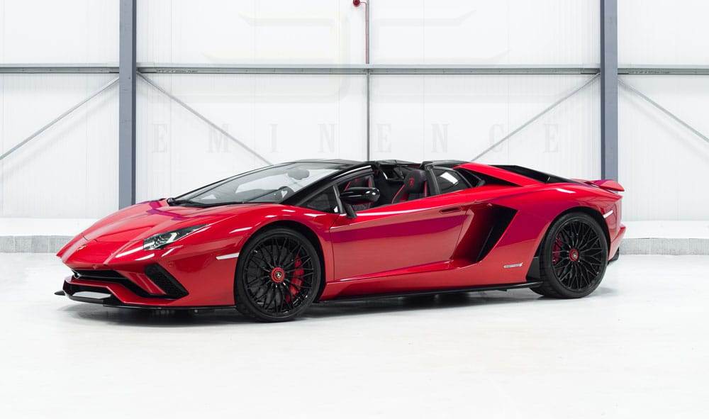 A red convertible sports car with black accents is parked in an indoor setting, available for hire.